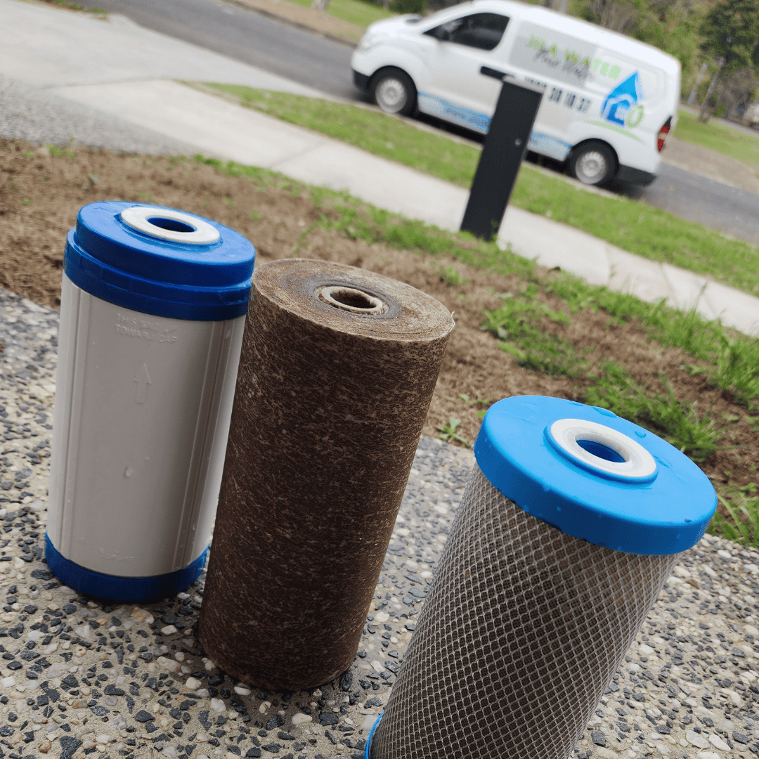 Used dirty water filter cartridges with Jila Water van in the background