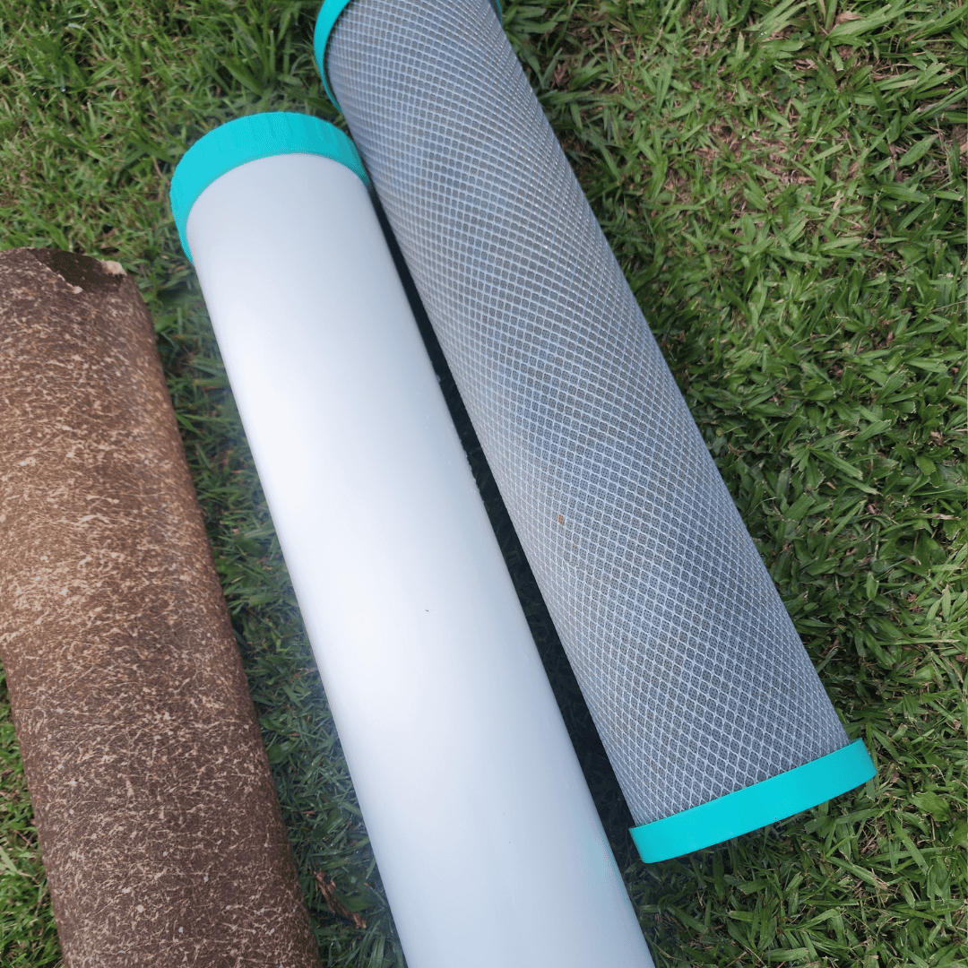 Clean and dirty whole home water filter cartridges laid on grass