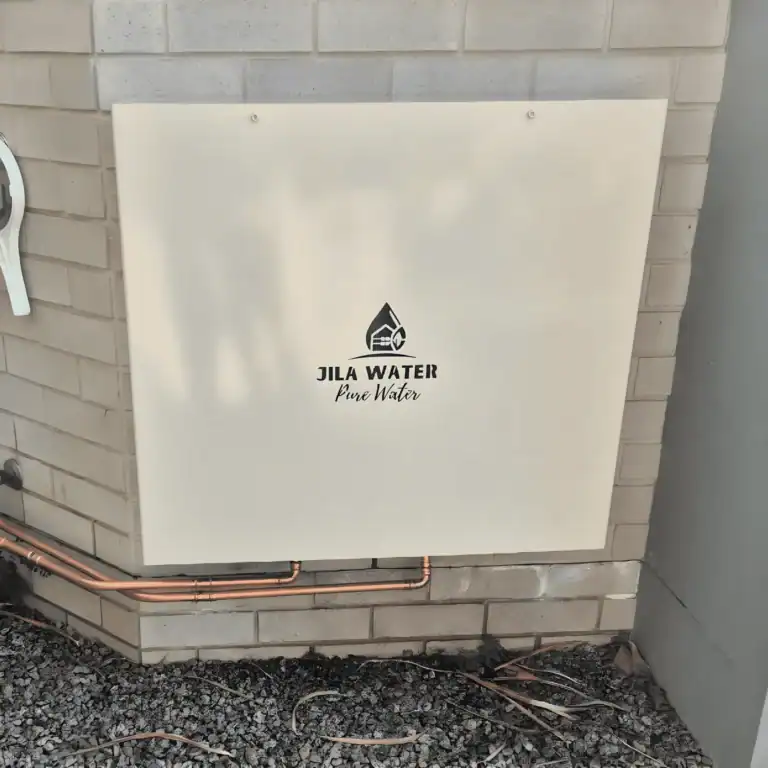 Classic cream Jila Water whole home water filtration system with copper pipework on a brick wall