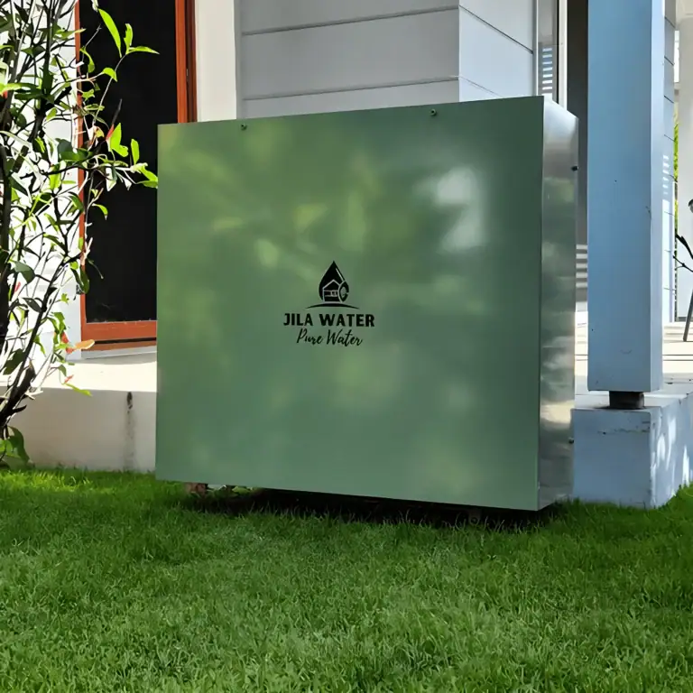 Pale Eucalypt green Jila Water whole home water filtration system installed on a lawn beside a Brisbane home