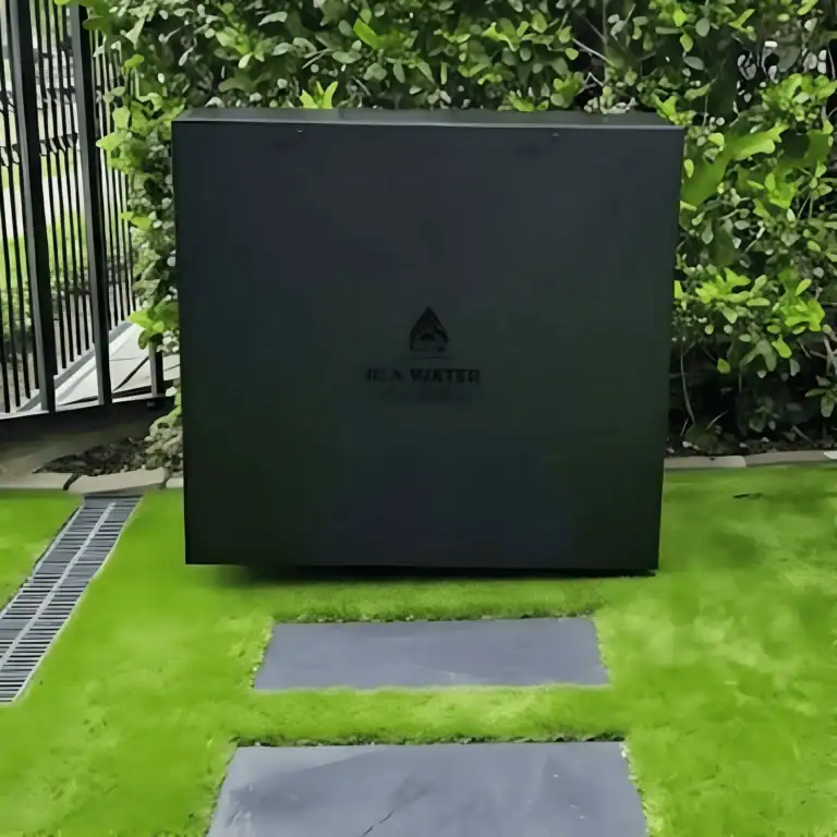 Satin black Jila Water whole home water filtration system installed beside a landscaped garden